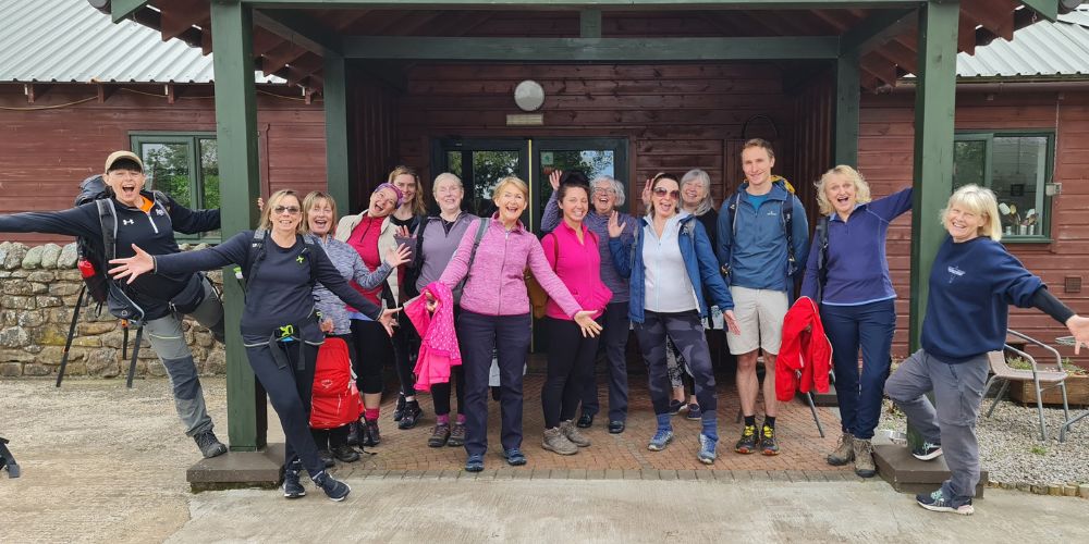 Image shows group of people smiling and ready for a walk in the countryside